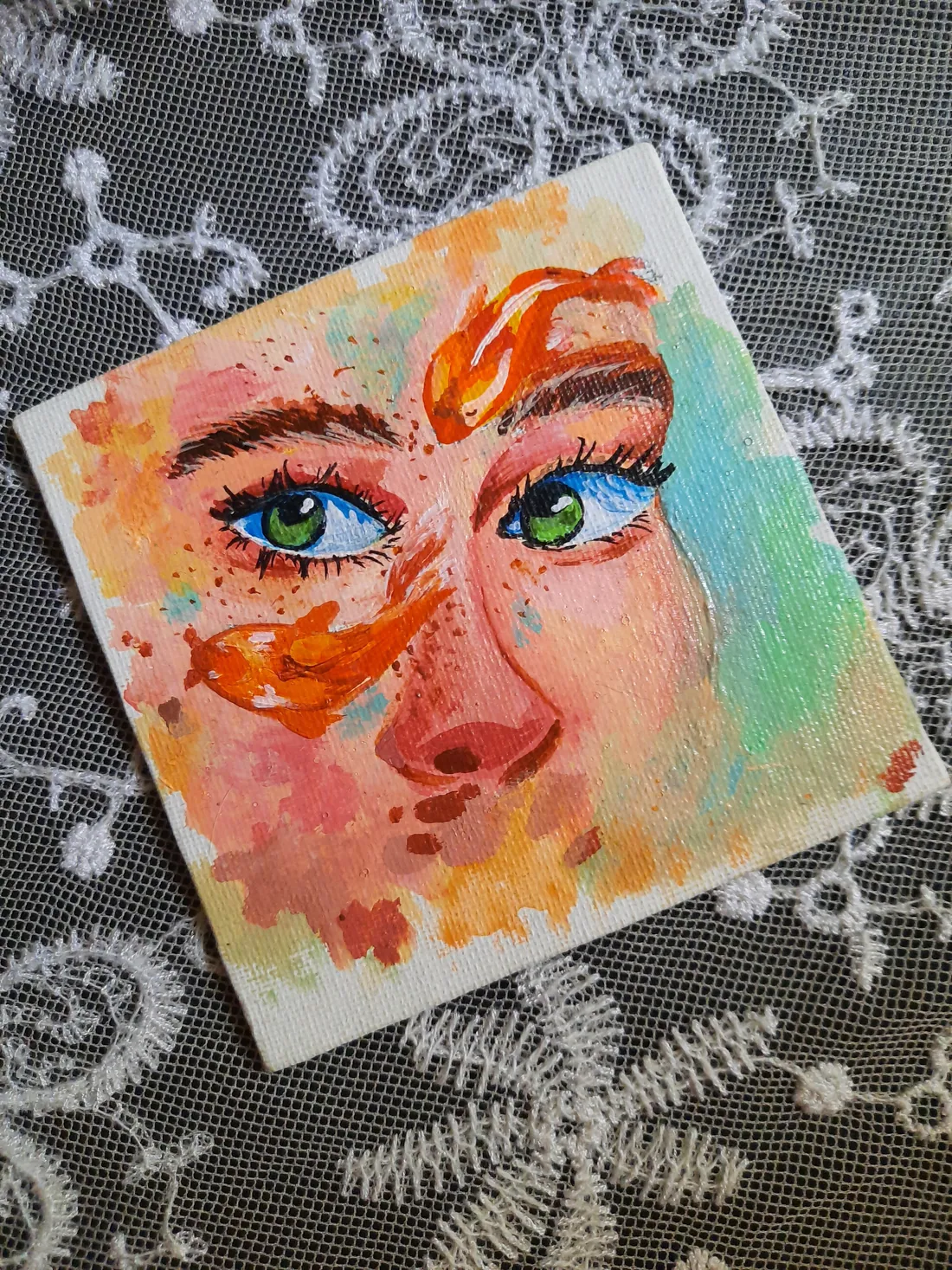 Acrylic painting of a face with green eyes and two orange koi